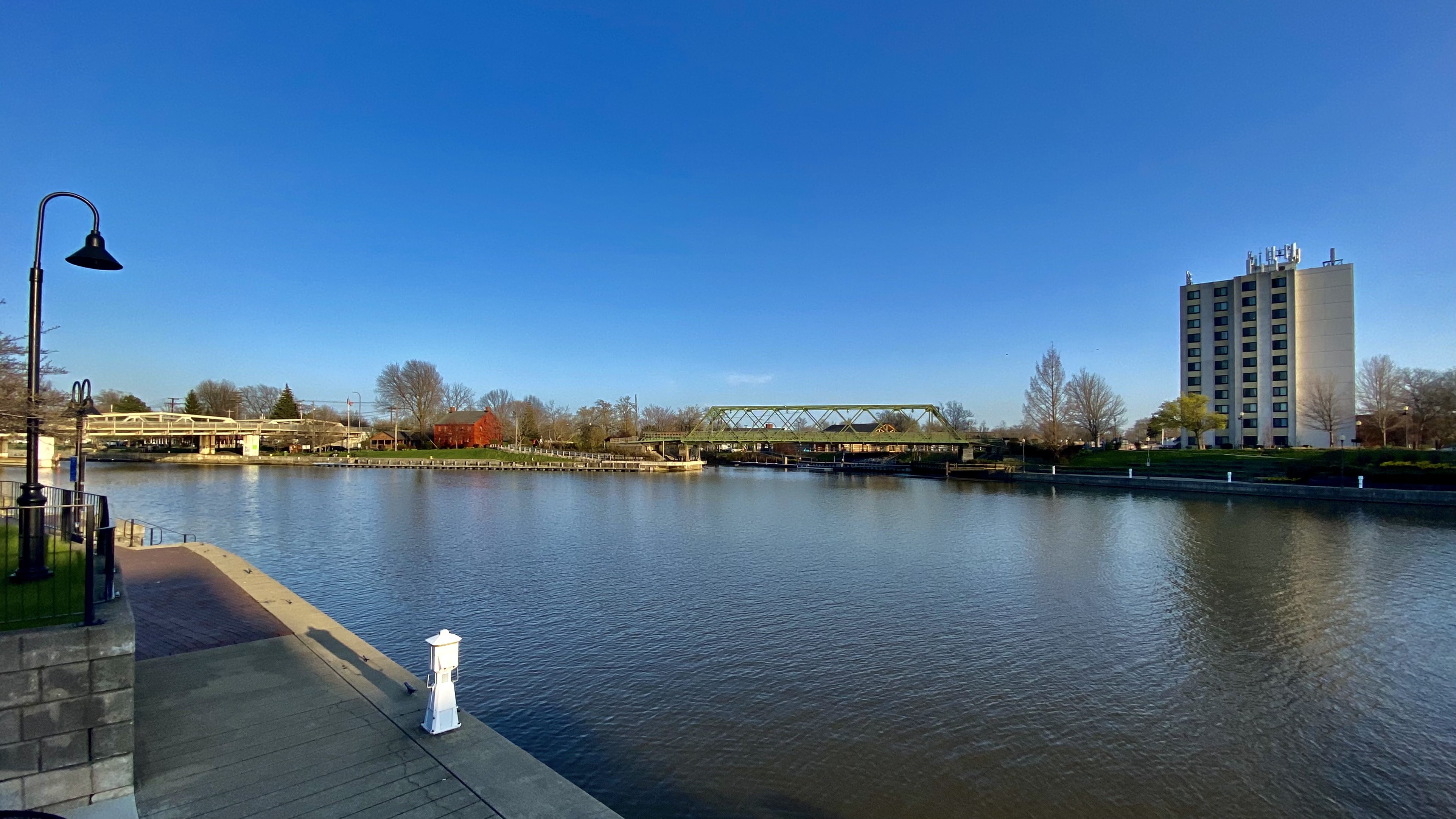 Modern view of Gateway Harbor on the Erie Canal as seen from North Tonawanda, New York, with calm water, docks, and greenery replacing the industrial lumber yards of the past