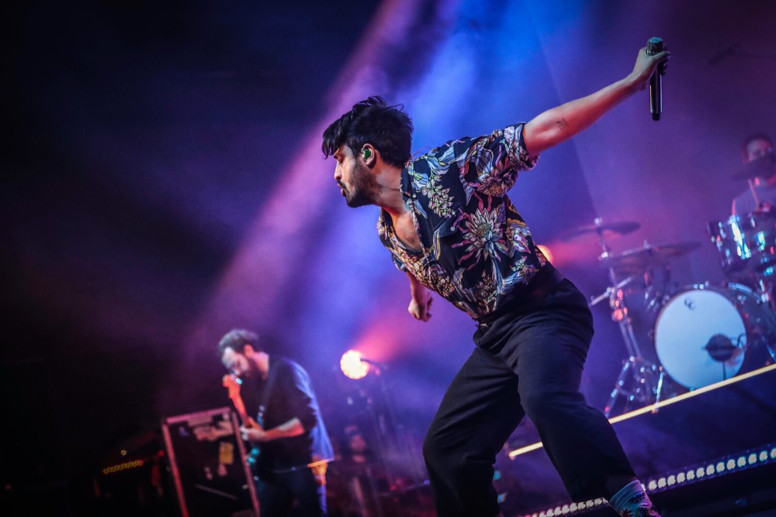 Young the Giant frontman Sameer Gadhia lunging across the stage during a live performance