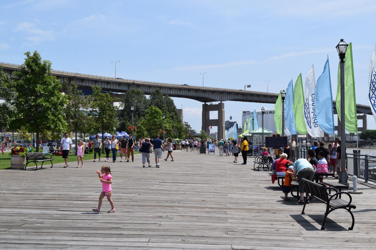 People walking the boardwalk at Canalside on the Buffalo waterfront on a summer day