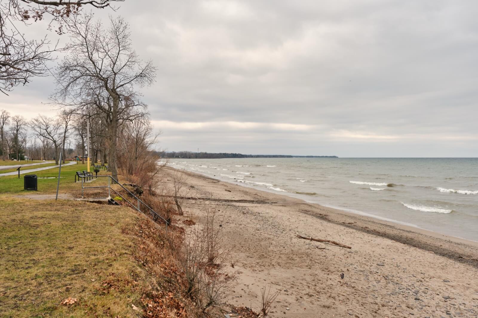 A rocky and sandy stretch of Point Gratiot Beach in Dunkirk, New York, with the wide open water of Lake Erie beyond